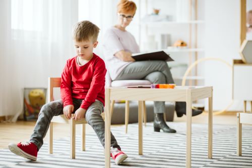 boy sitting by himself not looking at adult in room